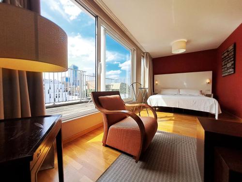 een slaapkamer met een bed, een stoel en een raam bij MAS Aparthotel EU in Brussel