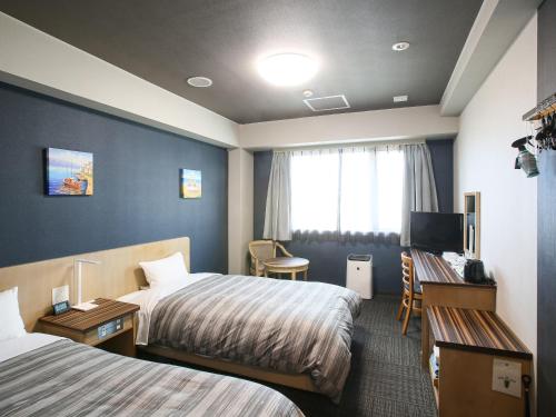 ein Hotelzimmer mit 2 Betten und einem Schreibtisch in der Unterkunft Route Inn Grantia Ishigaki in Ishigaki-jima