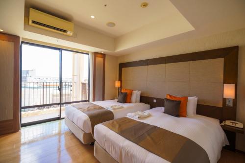 a hotel room with two beds and a large window at Moon Ocean Ginowan Hotel & Residence in Ginowan