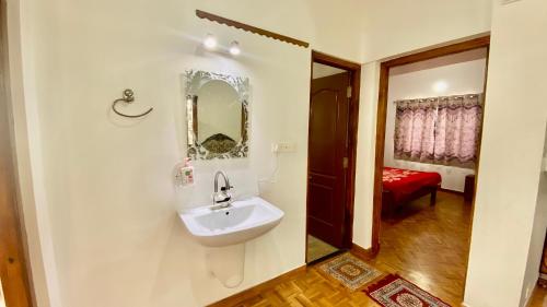 La salle de bains est pourvue d'un lavabo et d'un miroir mural. dans l'établissement La Flora kodaikanal, à Kodaikānāl
