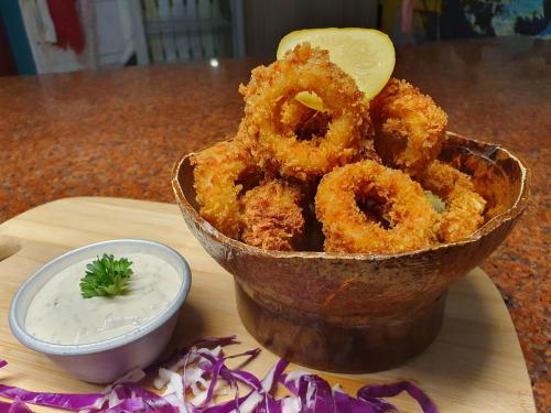 a bowl of onion rings on a table with a bowl of dipping sauce at Takatuka Beach Resort in Sipalay