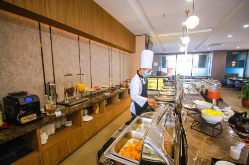 a chef standing in a kitchen preparing food at Asialink Hotel Batam by Prasanthi in Nagoya