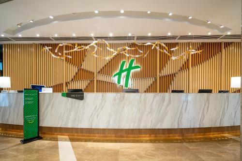 - un hall avec un comptoir avec une croix verte dans l'établissement Holiday Inn Shanghai Hongqiao Central, an IHG Hotel, à Shanghai