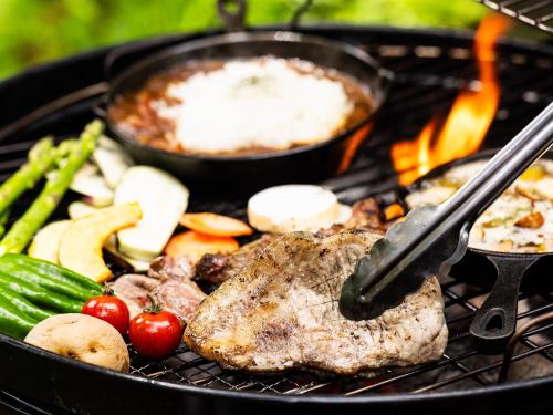 a steak and vegetables are cooking on a grill at Tokachi Nakasatsunai Glamping Resort Feriendorf in Naka-satsunai