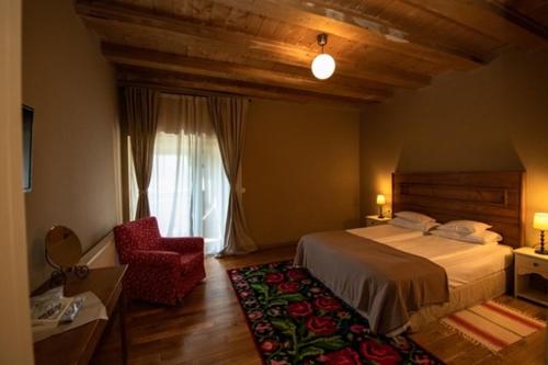 a bedroom with a bed and a chair and a window at Bucovina Lodge Pension in Vama