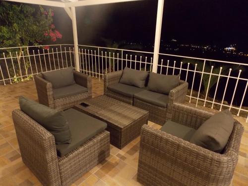 a patio with wicker chairs and couches on a balcony at Vasiliki View in Áyios Pétros