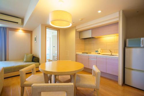 a kitchen and dining room with a table and a couch at Moon Ocean Ginowan Hotel & Residence in Ginowan