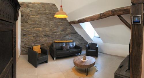 Elle comprend un salon doté d'un mobilier en cuir et d'un mur en pierre. dans l'établissement POSTRELAIS ARDENNES "Beau Séjour", à Burg-Reuland