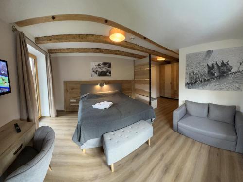 a bedroom with a bed and a couch and a tv at Hotel Landhaus Lungau in Sankt Michael im Lungau