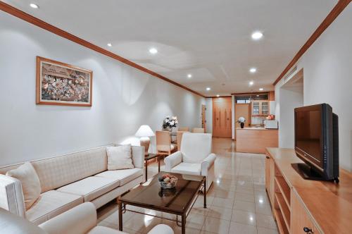 a living room with a couch and a tv at Riverine Place Hotel and Residence in Nonthaburi