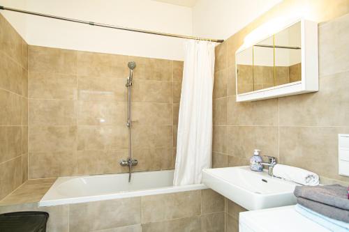 Un baño con bañera, lavabo y ducha. en Raimond Apartment Ottakring Top 22, en Viena