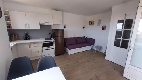 une cuisine avec des placards blancs et un canapé violet dans l'établissement Appartement BELLEVUE LES ISSAMBRES, à Roquebrune-sur Argens