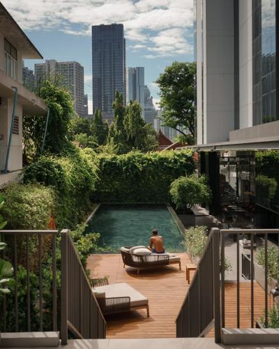 a man sitting in a bath tub in a pool on a balcony at Homm Sukhumvit34 Bangkok in Bangkok