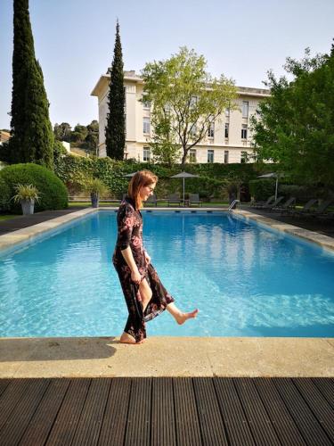 une femme qui marche devant une piscine dans l'établissement Au Centre de Villeneuve-lès-Avignon, à Villeneuve-lès-Avignon