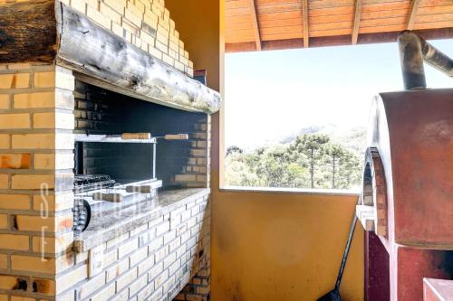 a kitchen with a brick fireplace and a window at Mansão da Imperatriz: Vintage, Termas e Natureza in Santo Amaro da Imperatriz