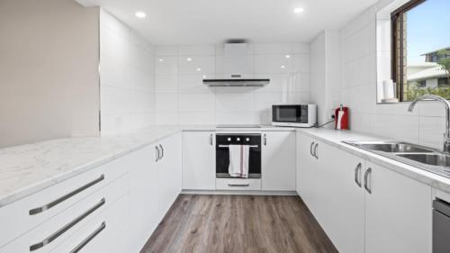 a white kitchen with white cabinets and a sink at Beachside Unit In The Center Of Town in Woorim