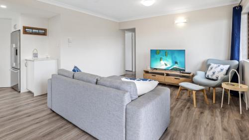 a living room with a gray couch and a tv at Beachside Unit In The Center Of Town in Woorim