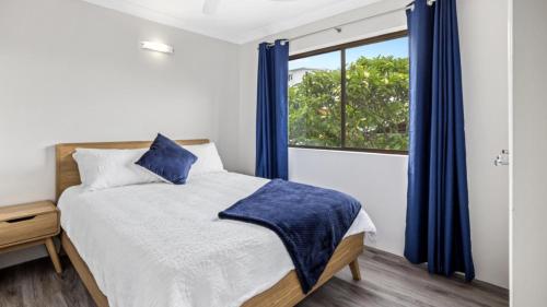 a bedroom with a bed with blue curtains and a window at Beachside Unit In The Center Of Town in Woorim