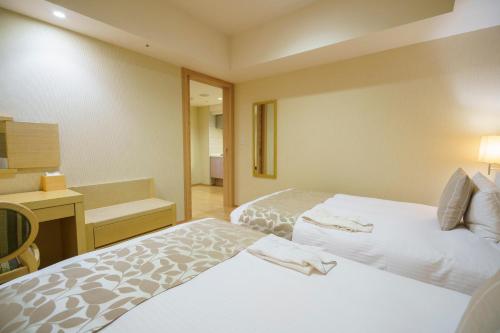 a hotel room with two beds and a desk at Moon Ocean Ginowan Hotel & Residence in Ginowan