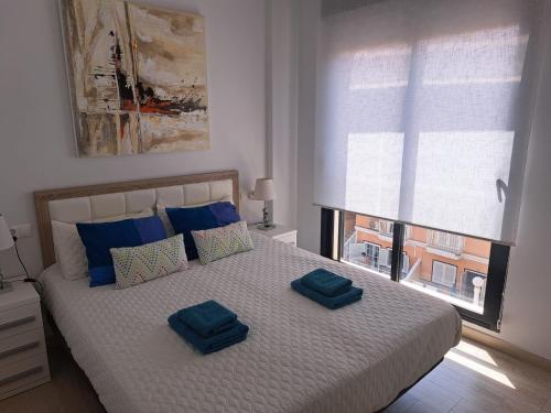 Un dormitorio con una cama con almohadas azules y una ventana en Mieszkanie LaMata, en La Mata