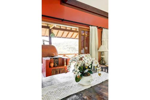a living room with a table with a vase of flowers at Mansão da Imperatriz: Vintage, Termas e Natureza in Santo Amaro da Imperatriz