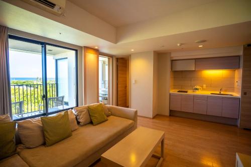 a living room with a couch and a kitchen at Moon Ocean Ginowan Hotel & Residence in Ginowan