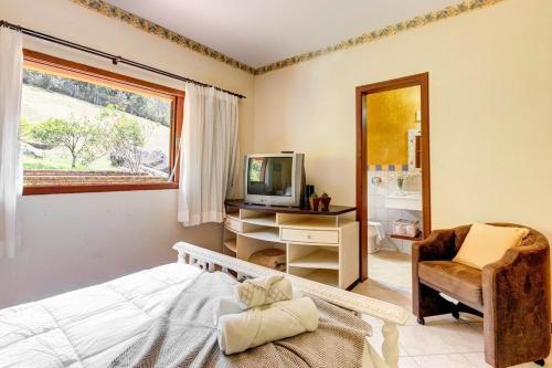 a bedroom with a bed and a tv and a chair at Mansão da Imperatriz: Vintage, Termas e Natureza in Santo Amaro da Imperatriz