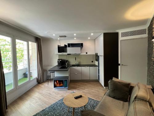 een woonkamer met een bank en een keuken bij Appartement T2 / La Défense in Courbevoie