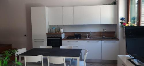 uma cozinha com armários brancos e uma mesa e cadeiras em Casa Mia Sirolo em Sirolo