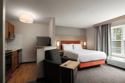 une chambre d'hôtel avec un lit et une cuisine dans l'établissement Candlewood Suites St Louis St Charles, an IHG Hotel, à Saint Charles