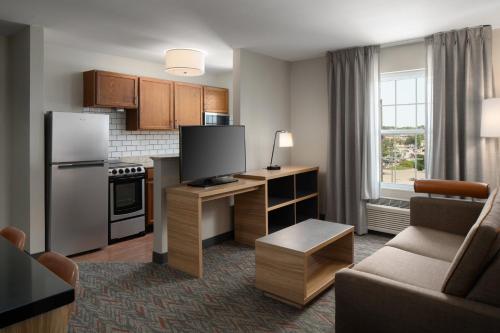 a living room with a kitchen with a tv and a couch at Candlewood Suites St Louis St Charles by IHG in St. Charles