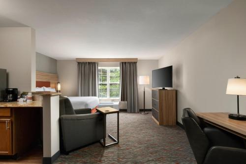 a hotel room with a bedroom with a bed and a desk at Candlewood Suites St Louis St Charles by IHG in St. Charles