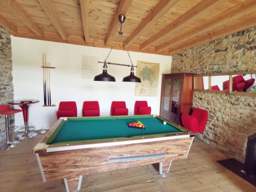 a room with a pool table and red chairs at La Maison des Biscuits in Loubaresse