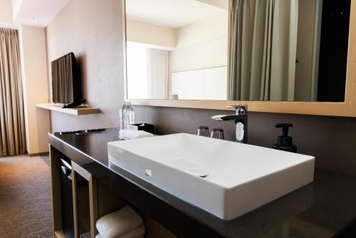 a bathroom with a white sink and a mirror at NOHGA HOTEL UENO TOKYO in Tokyo