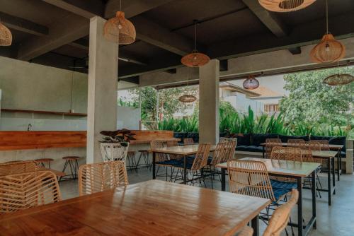 a restaurant with wooden tables and chairs and pendant lights at Sammy's Canggu in Canggu