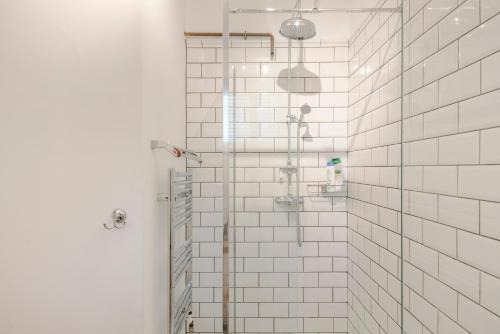 a bathroom with a shower with white tiled walls at Central Euston One Bedroom Home in London