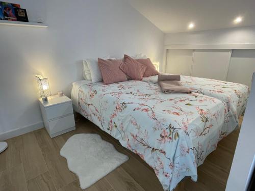 a bedroom with a bed with a floral bedspread at Pink Home in Santiago de Compostela