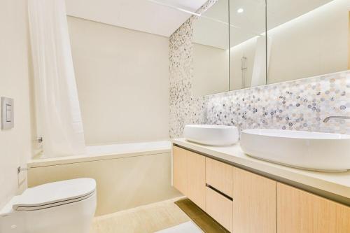 a bathroom with a sink and a toilet and a mirror at Voyage One Bedroom In Mayan in Abu Dhabi