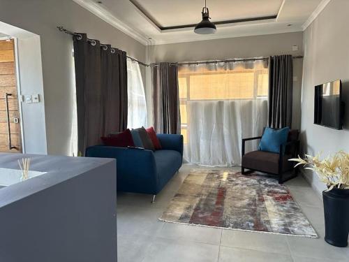 sala de estar con sofá azul y ventana en The Urban Hub in Block 5, en Gaborone