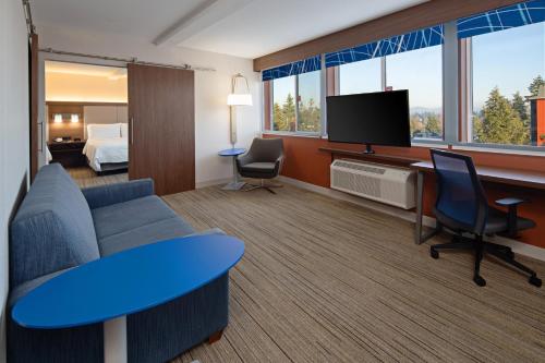 a hotel room with a couch and a tv and a bed at Holiday Inn Express Seattle - Sea-Tac Airport by IHG in SeaTac