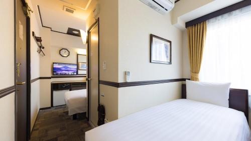 名古屋市にある東横INN名古屋丸の内のベッドとテレビが備わるホテルルームです。