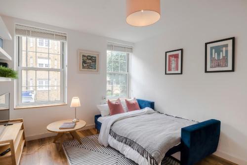 a bedroom with a bed and a desk and two windows at Central Euston One Bedroom Home in London