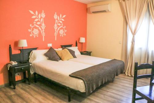 a bedroom with a large bed with orange walls at Hotel Venta Magullo in La Lastrilla