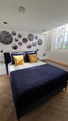 una camera da letto con un grande letto con lenzuola blu e cuscini gialli di LIEV Amsterdam Cozy boutique suite in The Pijp ad Amsterdam
