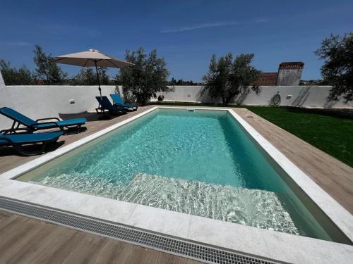 a swimming pool with two chairs and an umbrella at Casa Bé-Bia in Carvalhal