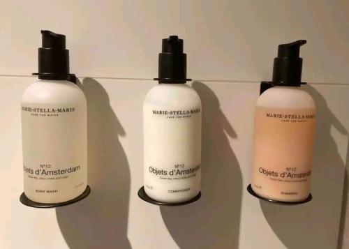 a group of three bottles of moisturizers on a shelf at LIEV Amsterdam Cozy boutique suite in The Pijp in Amsterdam