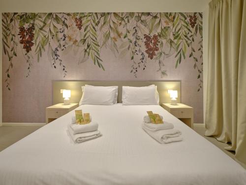a bedroom with a large white bed with two towels at ApartmentsArena - Residenza Dei Doganieri - Verona in Verona