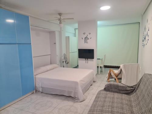 Un dormitorio con una cama, un televisor y un sofá. en Edificio El Sol, en Cullera
