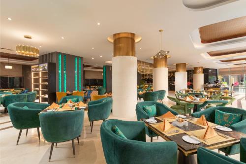 un restaurante con mesas y sillas verdes en Royal Tian Li Hotel en Yangón