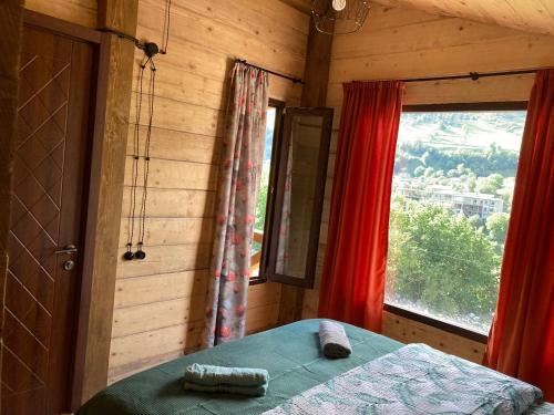 1 dormitorio con 1 cama y una ventana con cortinas rojas en MESTIA COTTAGE TiME, en Mestia